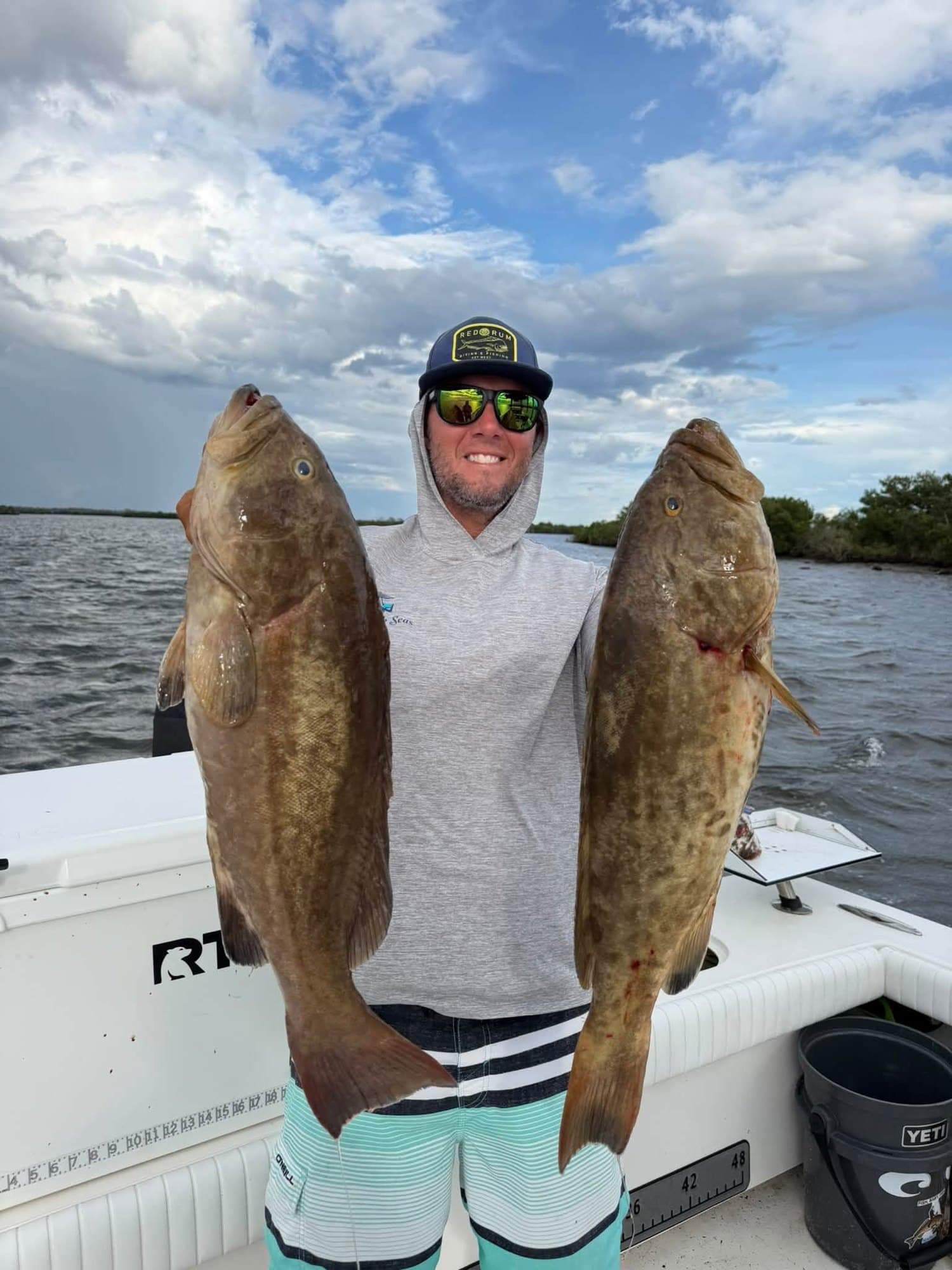 Capt. Alan Spangler holding two gag grouper on his boat